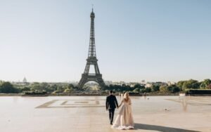 Eiffel Tower Visitor Guide: Couple walking near the tower in Paris at sunrise