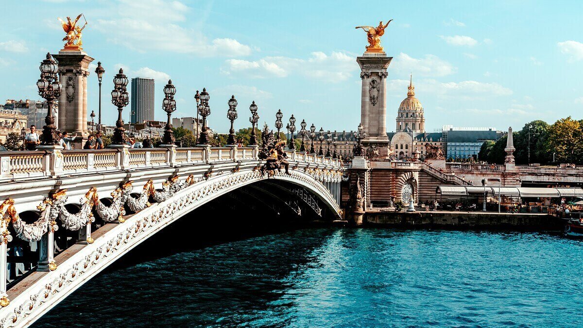 Ornate Alexandre III Bridge over the Seine River in Paris with Les Invalides in the background.