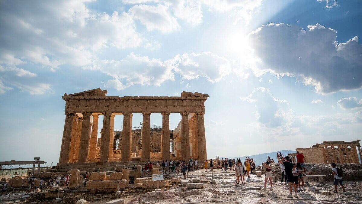 The Parthenon temple at the Acropolis of Athens with tourists under a sunny sky