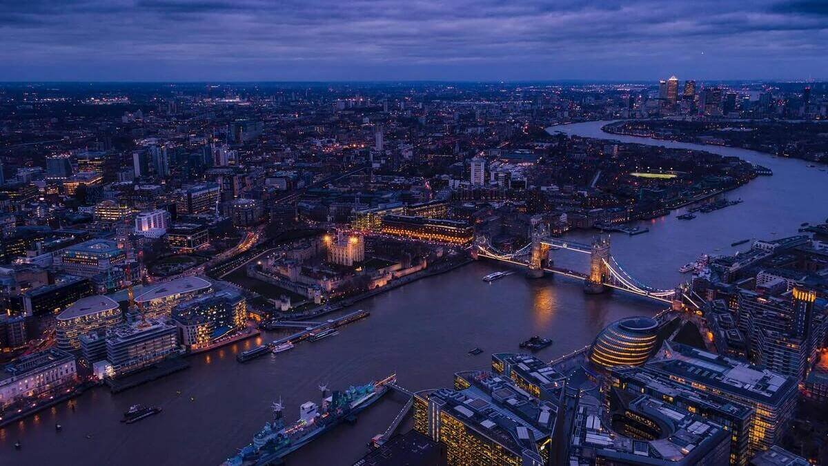 Night aerial view of London skyline featuring Tower Bridge and the River Thames.